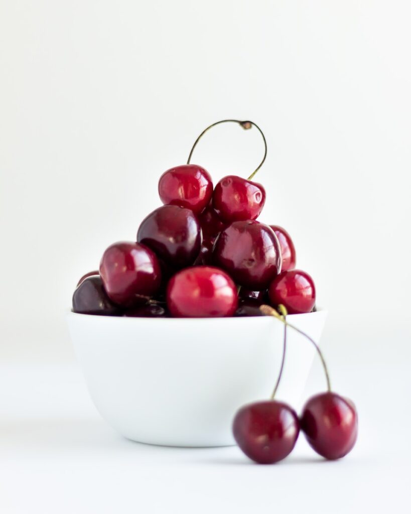 a white bowl filled with cherries on top of a table
