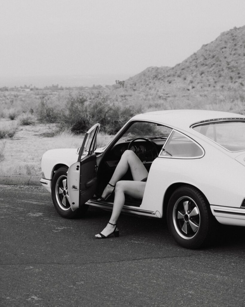 a black and white photo of a woman sitting in a car