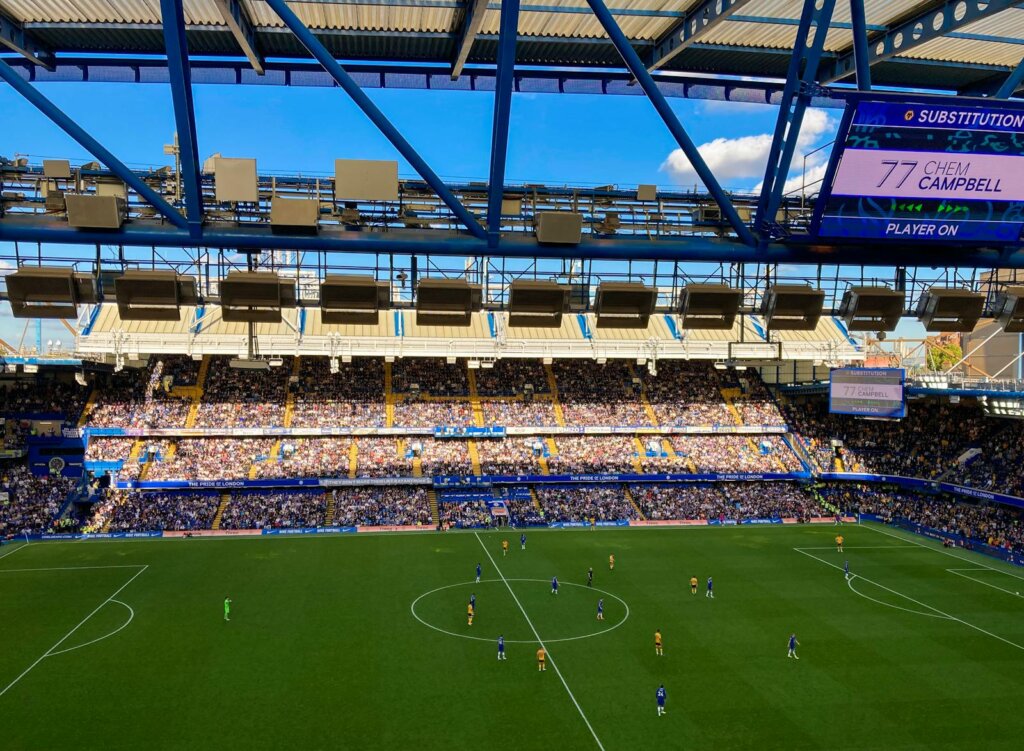 People watchng Athletes play Football on a Stadium