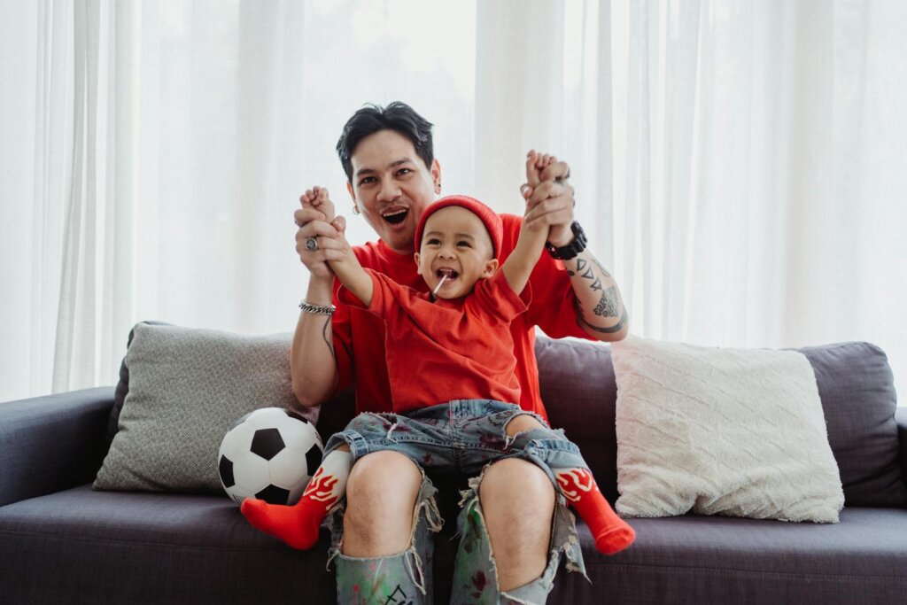 Father and Son Cheering while Watching a Football Match 