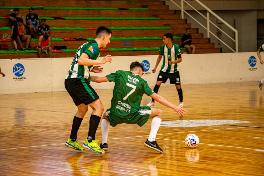 Exciting indoor futsal match with athletes competing on a polished wooden court.