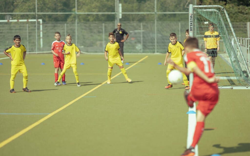 Dedicated teenage boys in activewear playing football together on field of outdoor stadium on sunny summer day